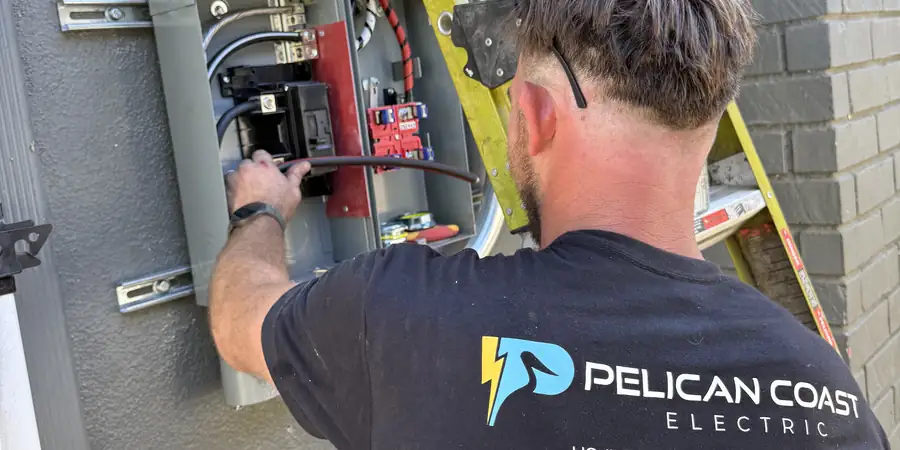 Pelican Coast Electric electrician landing conductors in an open meter main panel on a Newport Beach home