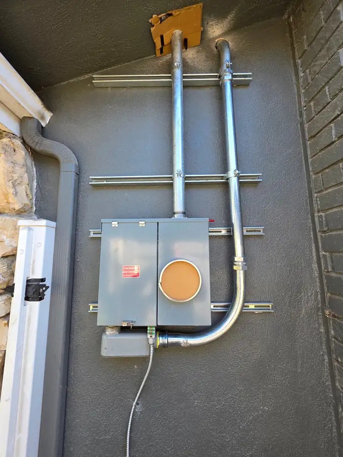 Finished exterior 200 amp panel with new conduit runs and a labelled emergency disconnect