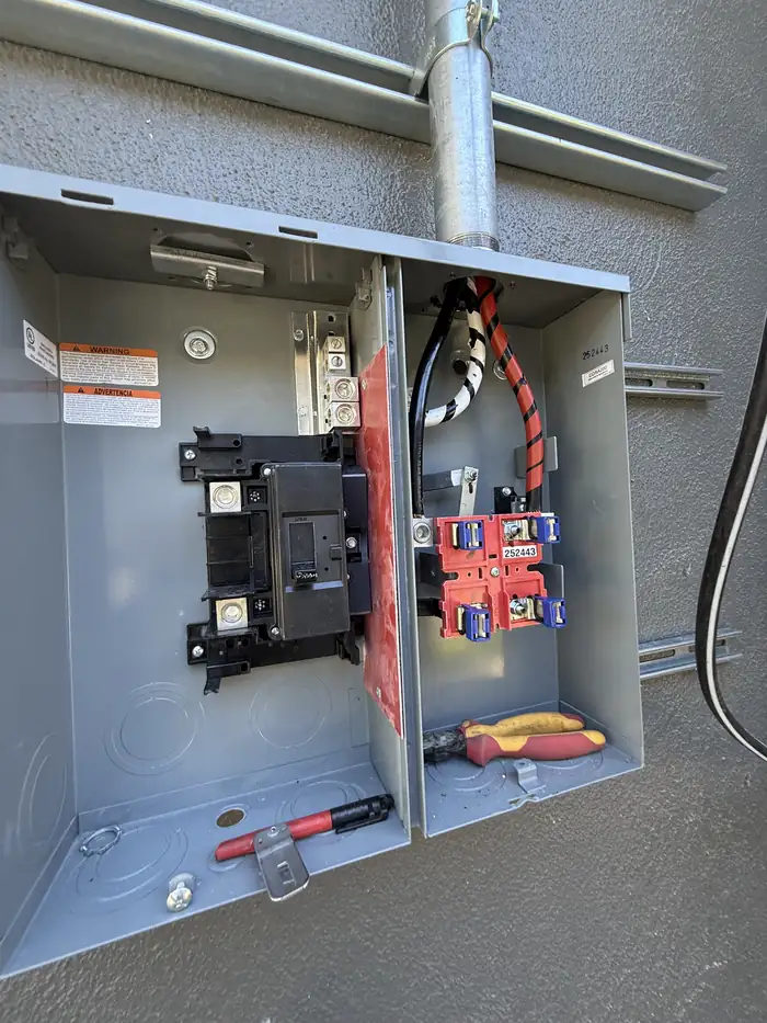 Open meter main enclosure with the main breaker and service conductors landed and taped