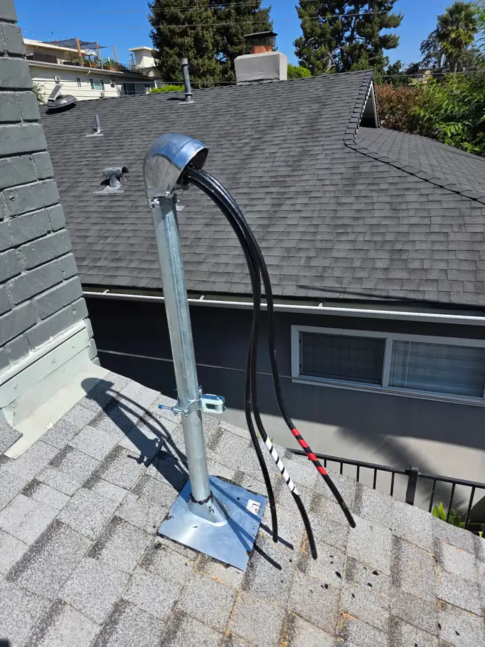 New service mast and weatherhead installed on a roof by Pelican Coast Electric