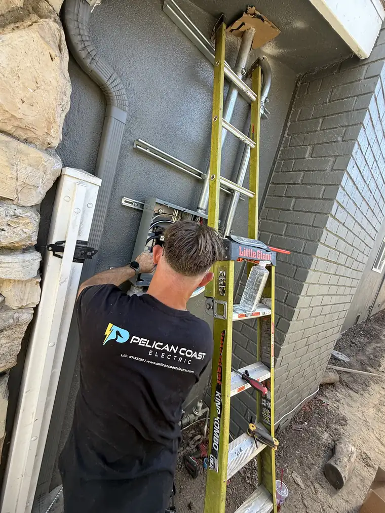 Pelican Coast Electric electrician working at an exterior service panel on a coastal Orange County home
